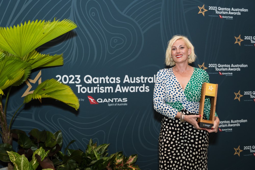 Person holding trophy standing in front of Qantas branded wall