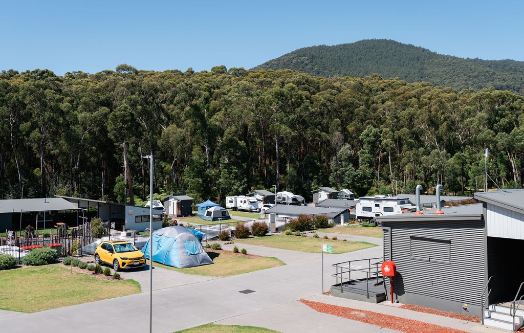Caravan park camp sites backed by bushland on a sunny day.